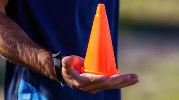 A man holding an orange cone in his hand photo