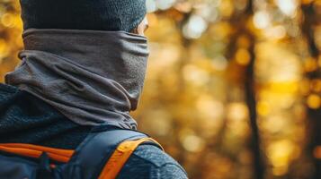 Person wearing a neck gaiter in a fall forest. photo
