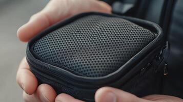 Close-up view of a small, square, black pouch held in hands. photo