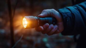 Close-up of a person holding a flashlight in the woods at night. photo