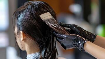 Woman's dark hair being treated with coloring product. photo