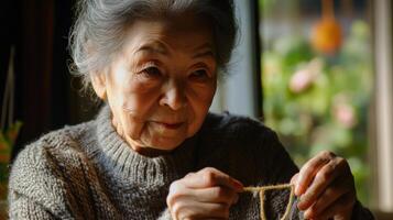 Elderly woman carefully threading yarn indoors. photo
