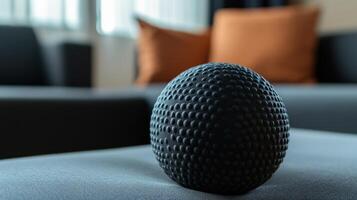 A black sphere rests on top of a gray cushioned surface photo
