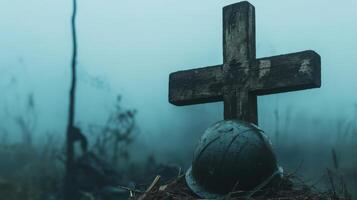 A weathered wooden cross with a helmet on a grave site photo