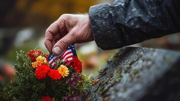 Hand placing a floral wreath on a grave in remembrance photo