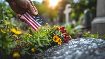 Hand placing a small american flag on a grave at sunset photo