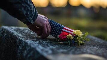 A person lays flowers and a flag on a tombstone photo