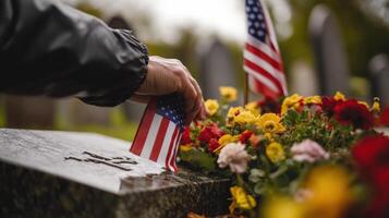 Hand Placing American Flag On A Tombstone Amidst Flowers photo