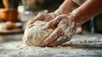 Close-up view of hands kneading dough on a floured surface. q photo