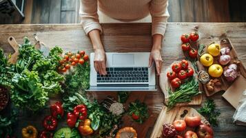 Person working on a laptop surrounded by fresh produce. photo