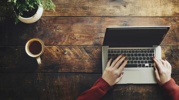 Wooden desk workspace with hands typing on laptop. photo