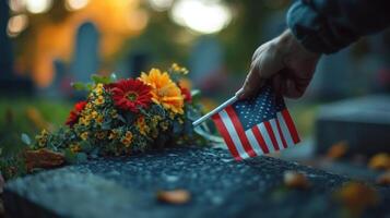 A hand placing a flag on a grave near some flowers photo