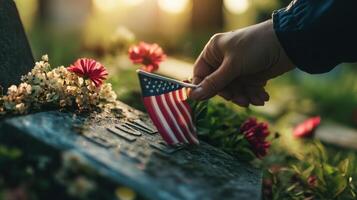 A hand places a small flag on a weathered tombstone photo