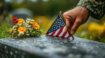 A hand placing a small flag on a cemetery headstone q photo