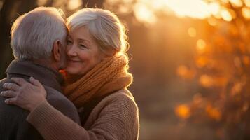 An elderly couple warmly embracing each other outside during sunset time photo