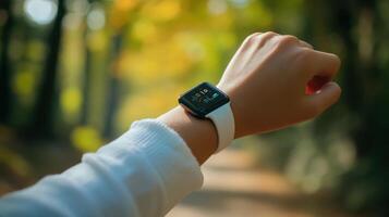Person is wearing a smartwatch outdoors in a park setting photo