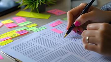 A person writes on a document using a pen at their desk photo