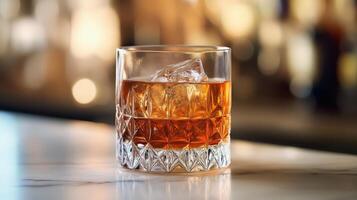 A crystal glass of amber liquid with ice on a marble surface photo