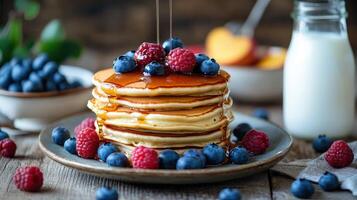 Delicious stack of pancakes with berries and syrup is shown photo
