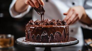 A chef carefully applies chocolate frosting to a delicious cake photo