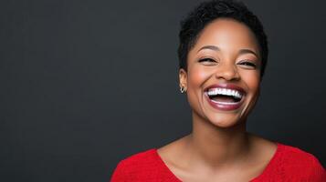 Joyful Laughing Woman Portrait Featuring Bright Smile and Red Top Against Solid Gray Backdrop photo