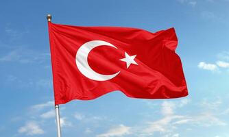Waving Turkish national flag with crescent and star against clear blue sky background photo