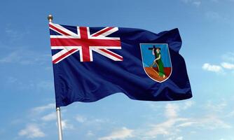 Montserrat flag waving against sky with Union Jack and island emblem visible photo