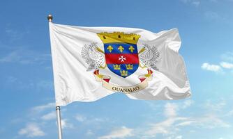 Official flag of Saint Barthelemy featuring the coat of arms with pelicans, fleur-de-lis, crowns, and the word Ouanalao photo