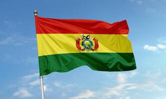 Bolivia national flag with red, yellow, and green horizontal stripes and detailed coat of arms waving in the sky photo