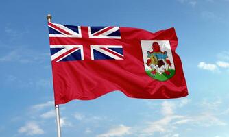 Bermuda national flag with Union Jack and coat of arms featuring a lion and ship on a red field flying in the sky photo