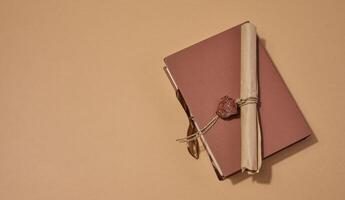 A closed book with a sealed scroll lying on top, on a neutral background. photo