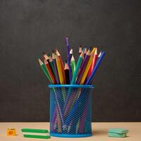 Multi-colored pencils in a blue metal cup, sharpener and erasers symbolizing study or creativity photo
