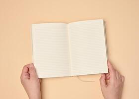 Hands hold a blank open notebook on a neutral background photo