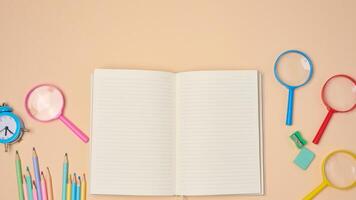 Open notebook with pastel-colored pencils, green sharpener, and turquoise eraser on a beige background. photo