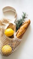 Reusable mesh bag with lemons, crusty baguette, sprig of rosemary, great for eco conscious shopping and sustainable living enthusiasts, emphasizing freshness, minimalism, natural ingredients together. photo