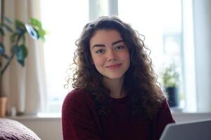 A woman with curly hair sitting on a couch with a laptop photo