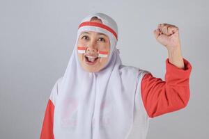 Indonesian woman in hijab with face paint smiling and raising fist in celebration photo