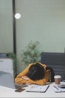 A woman is sleeping on a desk in an office photo