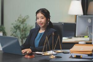 Asian woman in business suit sitting at desk with laptop photo