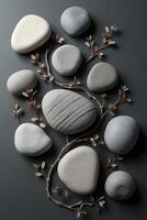 Arrangement of smooth gray stones with delicate branches on a dark surface photo