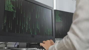 A person typing on a computer screen with green code video