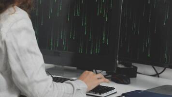 A woman is typing on a keyboard in front of two computer monitors video