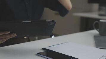 A person is holding a tablet computer in front of a laptop video