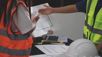 Two people in safety vests and hard hats are working on a blueprint video