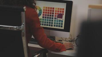 A woman is working on a computer with a color palette on the screen video