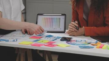 Two people working on a project at a table with colorful paper video