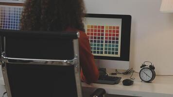 A woman sitting at a desk with a computer screen and a color palette video