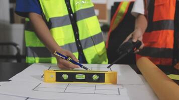 Two people working on construction plans with a level video