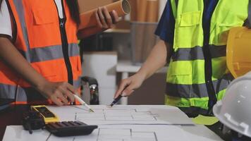 Two construction workers are working on a blueprint video