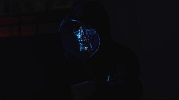 mascarado hacker às computador portátil dentro Sombrio quarto simulando digital ataque e Internet segurança violação video